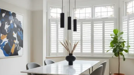 Dining room with white café style shutters on a bay window, leaded glass above