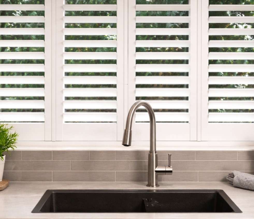 White plantation shutters installed above a kitchen sink