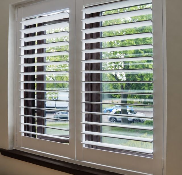 White full-height plantation shutters with louvres open, looking out to the street
