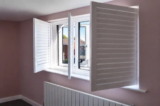 Pink bedroom in Stourbridge with a full height white shutter bay window, the two side panels hinged open to show the casement windows behind