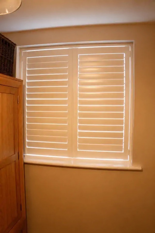 Home office in Stourbridge with full height white plantation shutters across a four-panel bay window, all panels closed