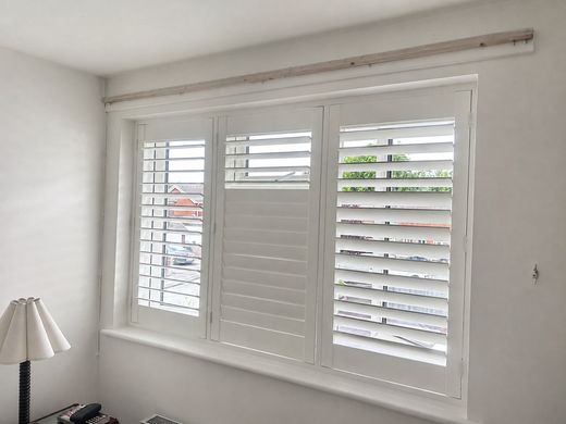 Wednesbury bedroom with a three-panel full height composite shutter in Silk White, lower louvres closed and upper louvres tilted open showing the split-tilt feature
