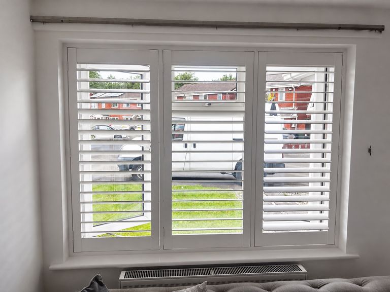 Wednesbury living room with three-panel full height composite shutters in Silk White, lower louvres closed and upper louvres tilted open