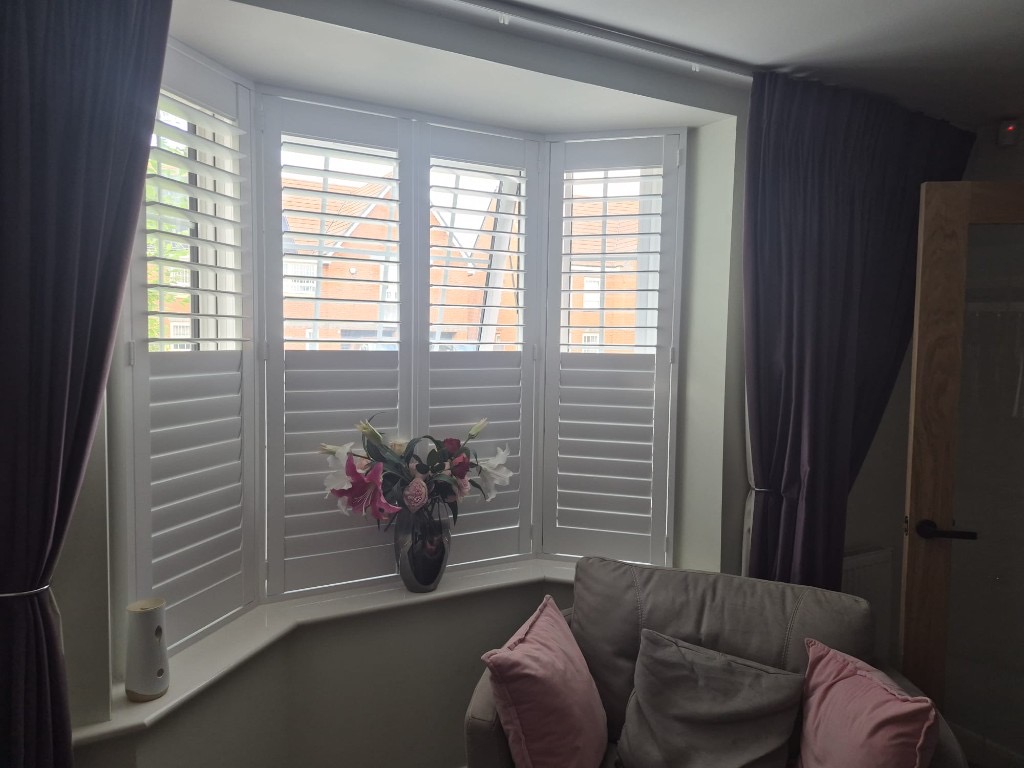 Baggeridge living room bay shutters in Pure White, all louvres tilted open to the street