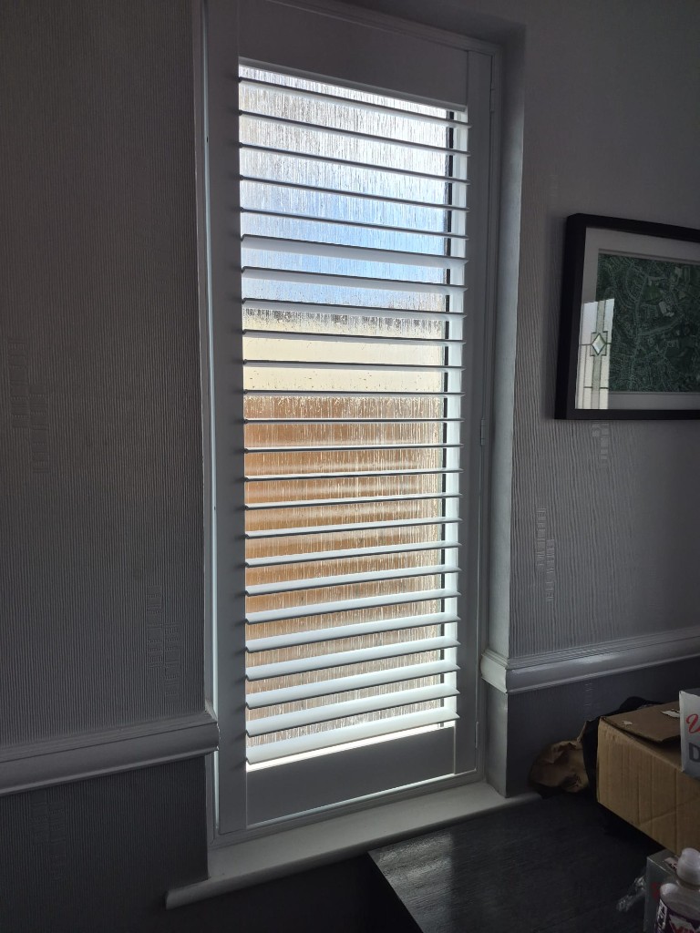 Halesowen downstairs hallway with a single Pure White full height shutter on a narrow window, louvres tilted open