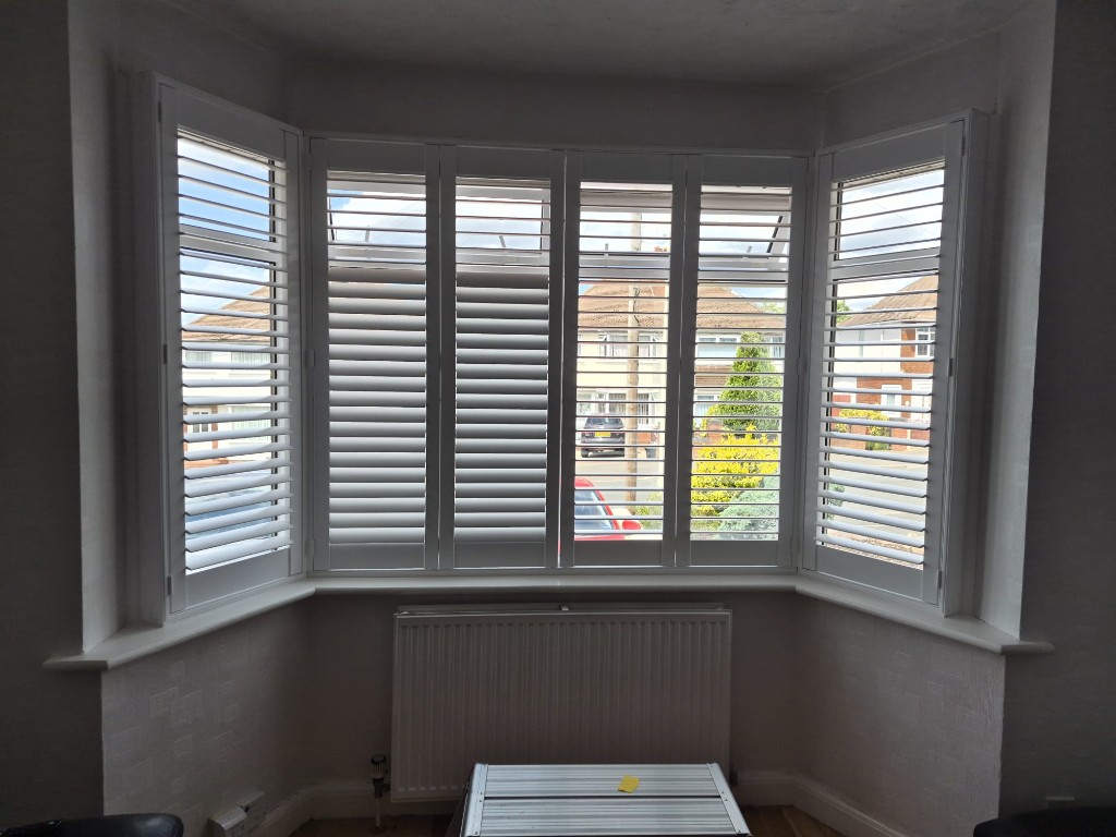 Halesowen downstairs bay window with six-panel Pure White shutters, louvres tilted open to the street