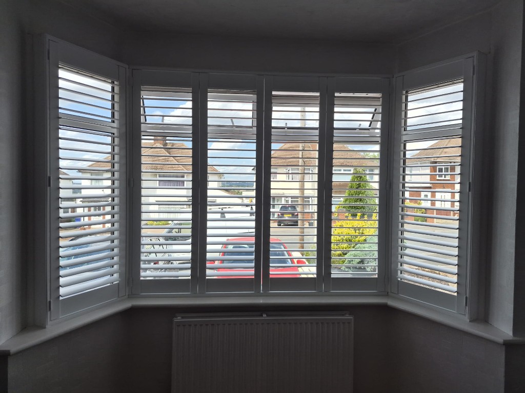 Halesowen downstairs bay with Pure White shutters and split tilt, upper louvres open above the radiator