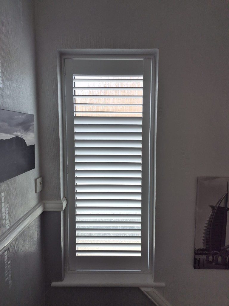 Halesowen stairwell window with a single Pure White full height shutter, split tilt with upper louvres open