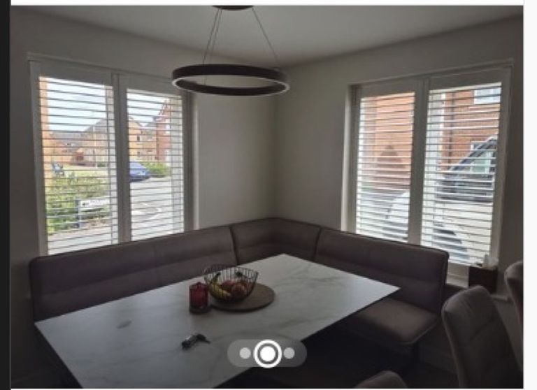 Pure White full height shutters on corner dining windows with louvres tilted open, marble dining table below