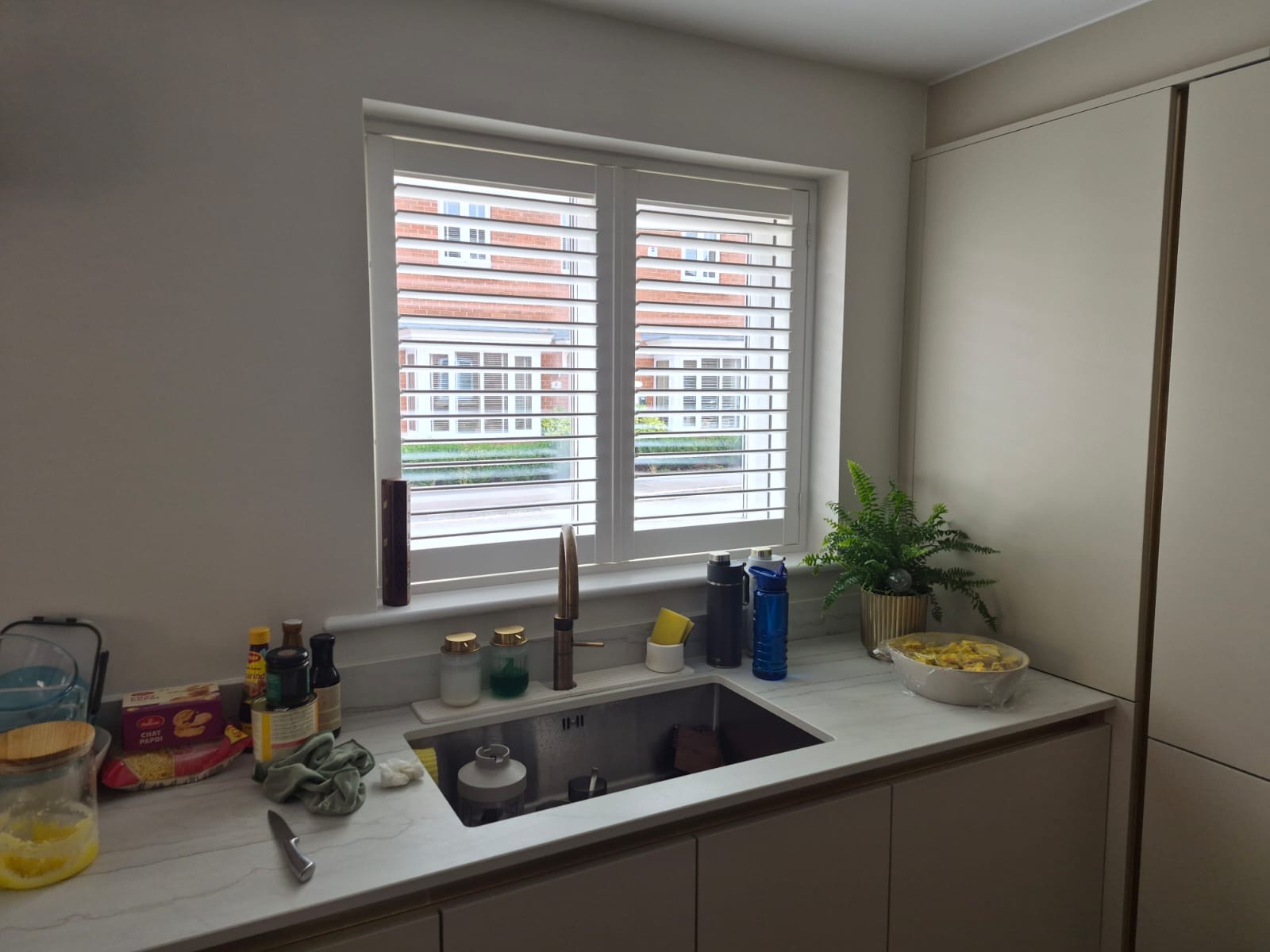 Kingswinford kitchen with full height composite shutters in Silk White over the sink, louvres tilted open