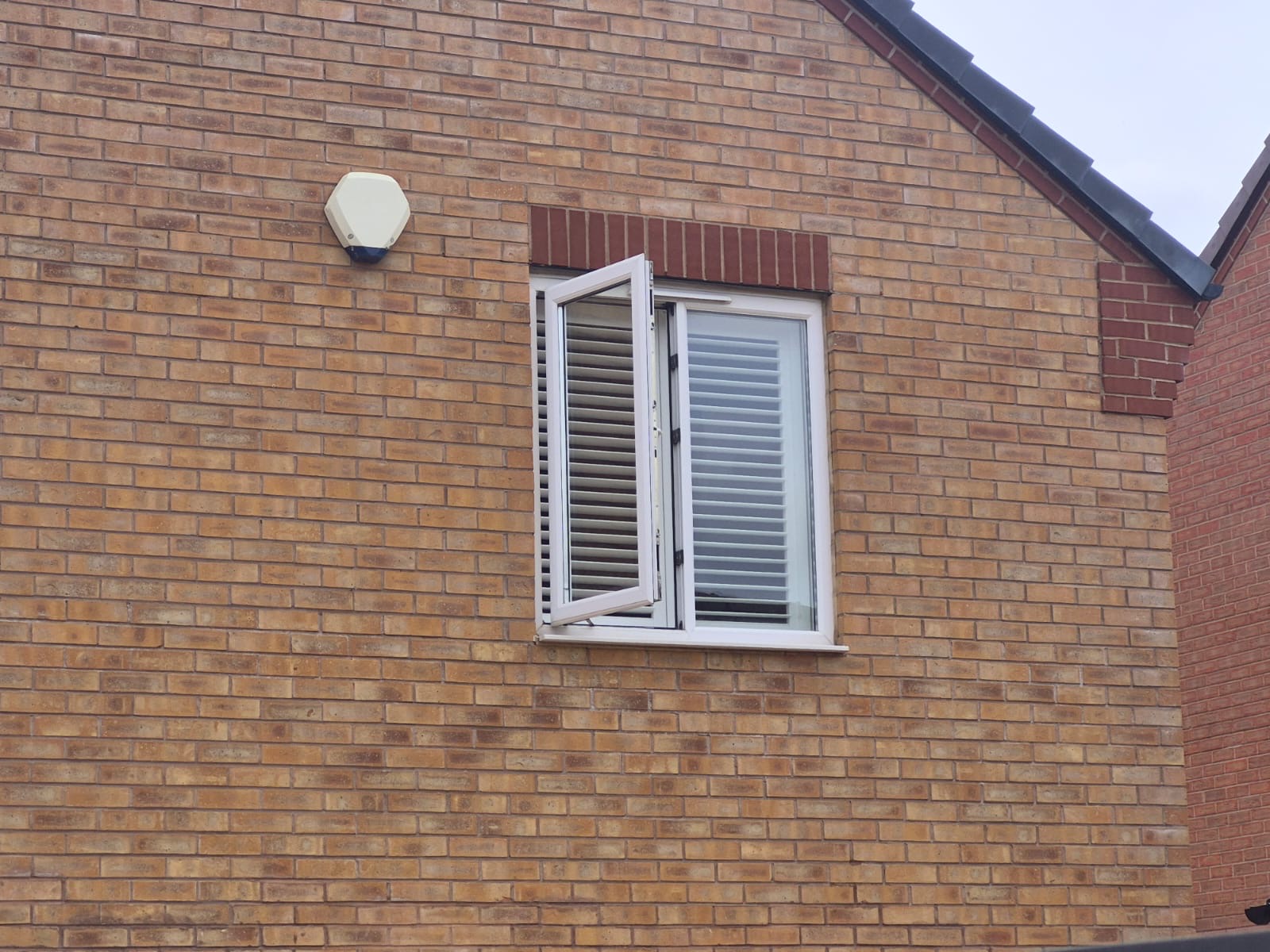 Kingswinford house exterior with Silk White composite shutters visible through an open casement window