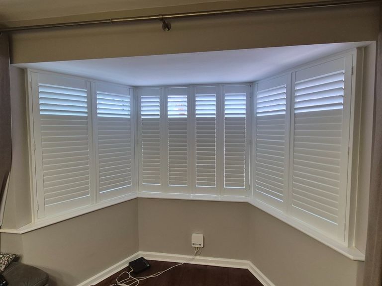 Netherton living room bay window with Pure White full height composite shutters, upper louvres open and lower louvres closed