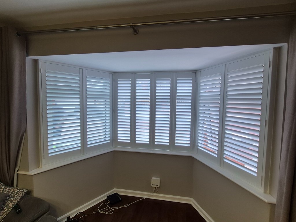 Netherton living room bay window with Pure White full height composite shutters, louvres partially open