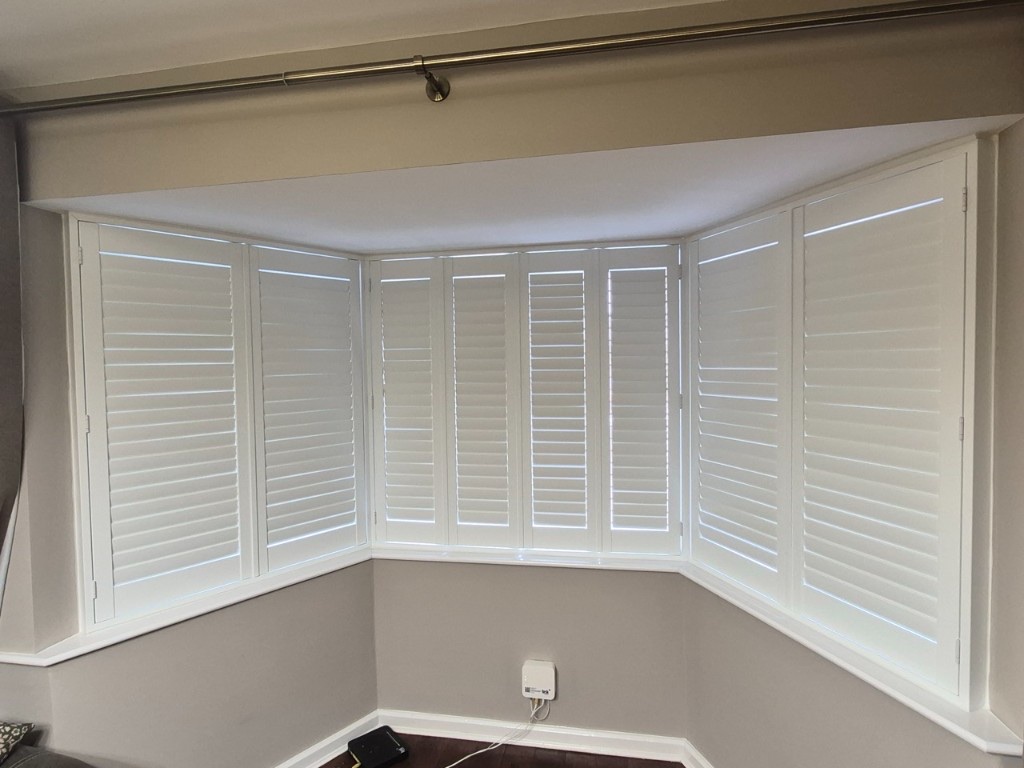 Netherton living room bay Pure White composite shutters with louvres closed for privacy