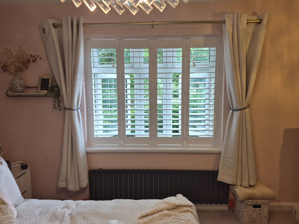 Oldbury bedroom with four-panel bifolding engineered wood shutters in Pure White, split tilt with lower louvres closed and upper louvres open