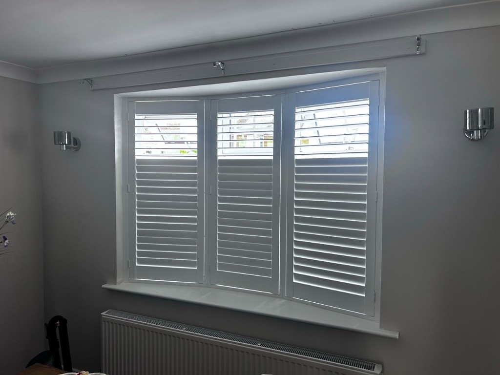 Dining room bay Pure White composite shutters with split tilt, upper louvres open and lower louvres closed