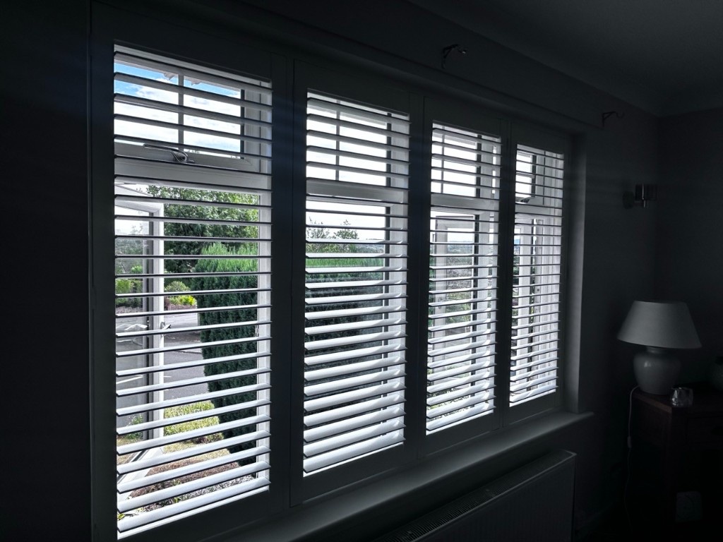 Living room Pure White composite shutters with louvres open and daylight through the panels