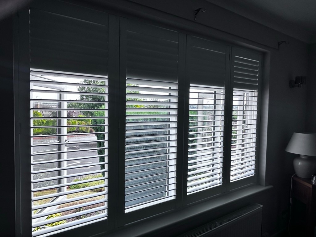 Living room Pure White composite shutters with one panel open, showing split tilt