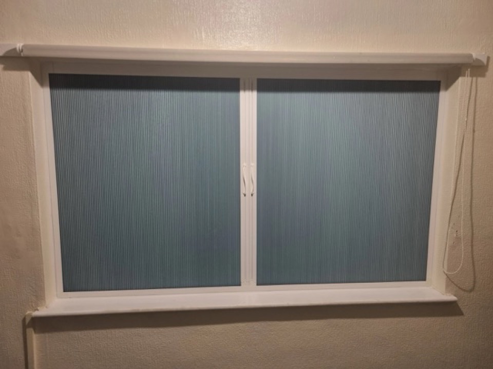 Integrated blue pleated blinds fitted in a white bedroom window frame