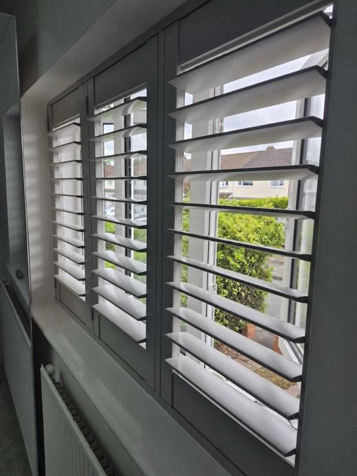 Great Barr bedroom with full height plantation shutters in a soft Sea Mist grey, louvres tilted open
