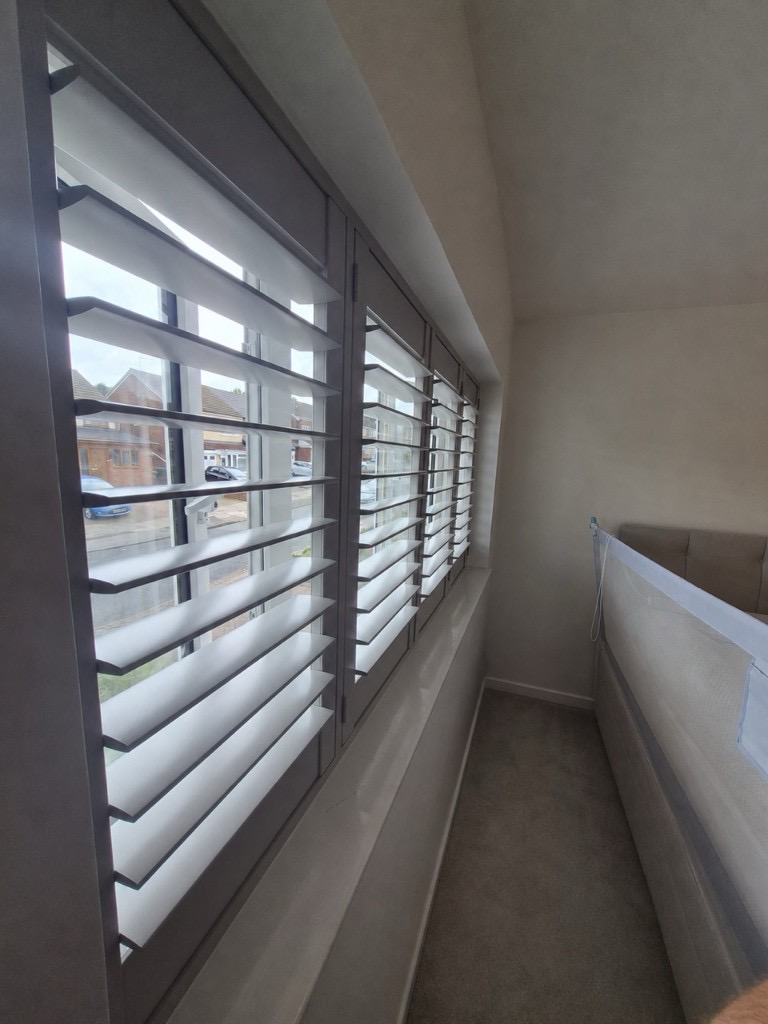 Great Barr bedroom with full height Sea Mist shutters along the window wall, louvres tilted open beside the bed