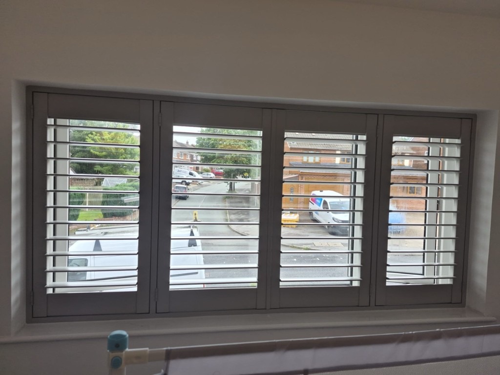 Great Barr bedroom with four-panel full height shutters in Sea Mist, louvres tilted open with a mirrored wardrobe to the left