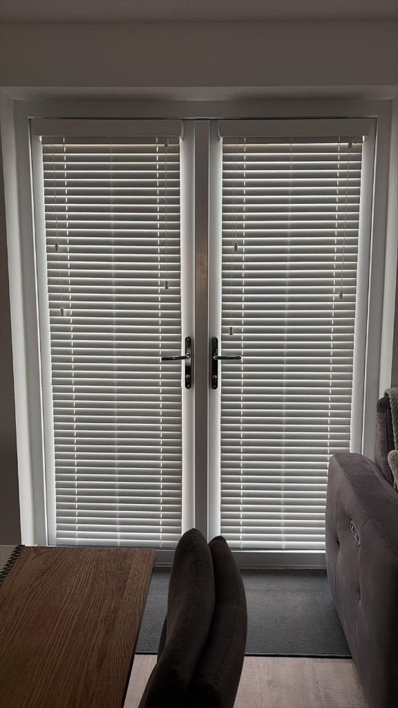 Stafford French patio doors with white faux wood venetian blinds face-fixed to each door, slats tilted for privacy