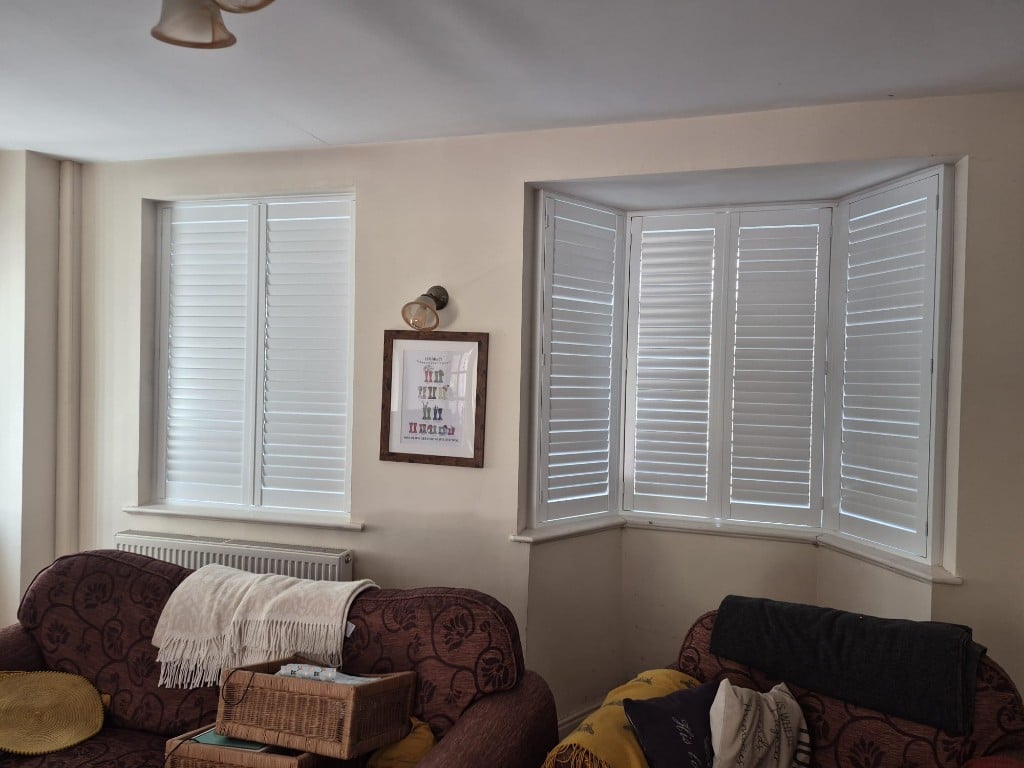Pure White composite shutters on living room flat window and bay with split tilt, upper louvres open