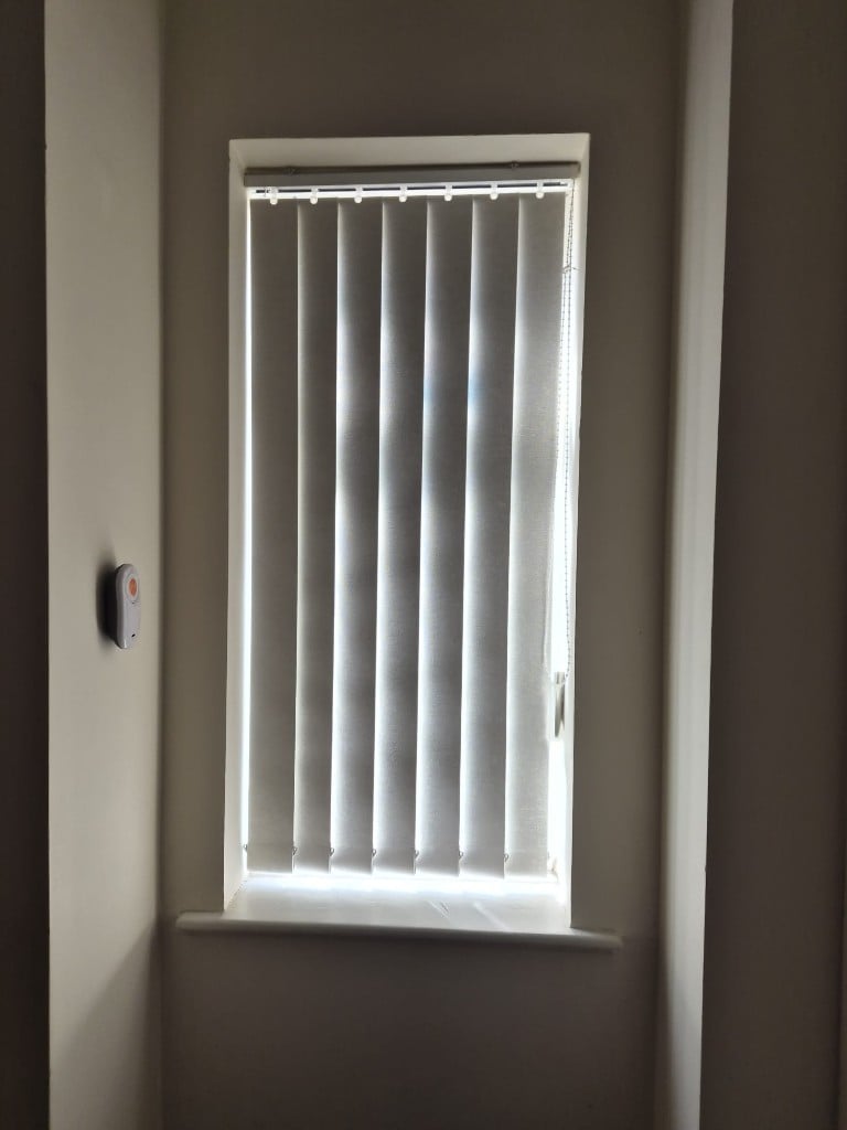 White vertical blind fitted to a smaller living room window