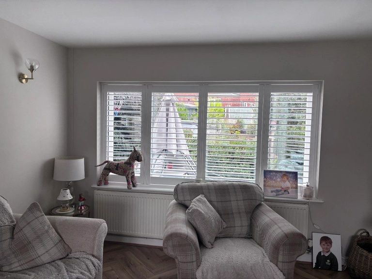 Full height Pure White shutters with 76mm louvres and a hidden tilt rod on a four-panel living room window facing the garden in Halesowen
