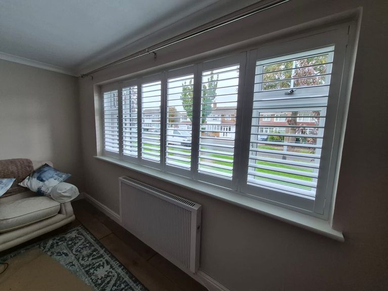 Full height Pure White Boston shutters with 76mm louvres across a three-metre living room window in Tipton, louvres open