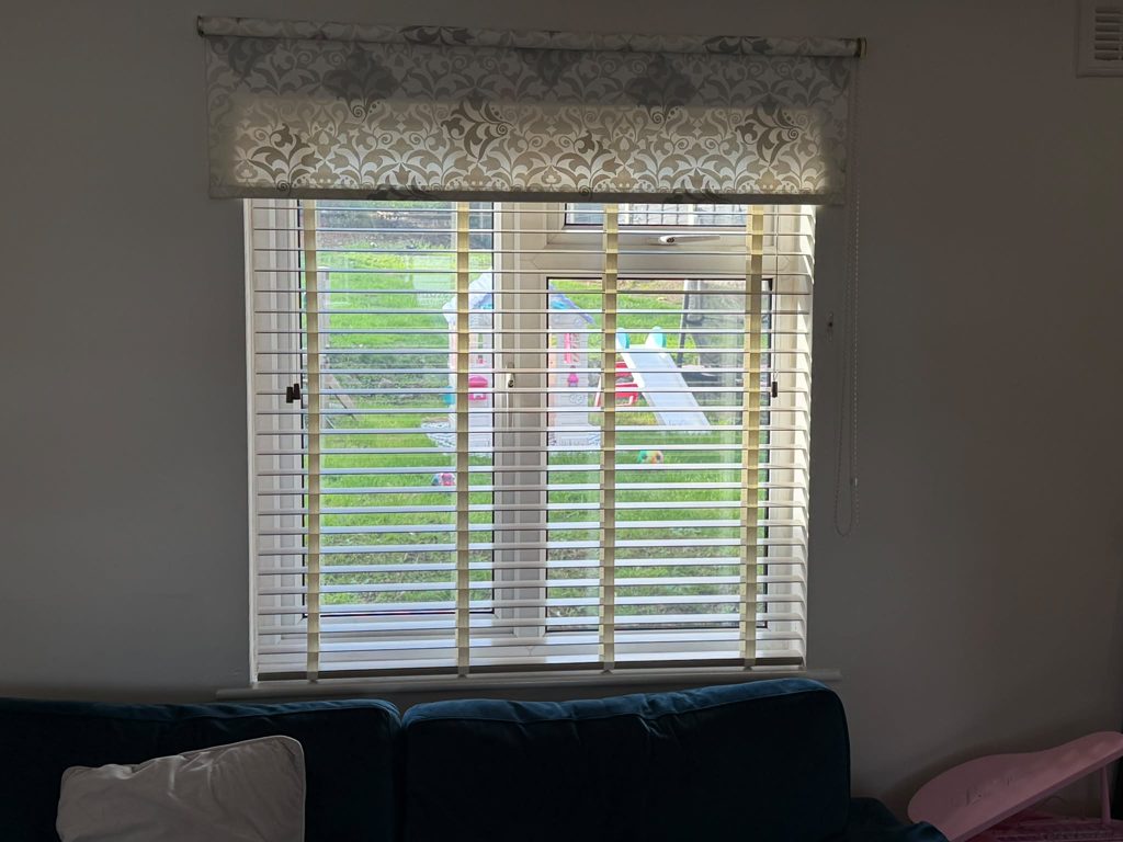 Living room back window in Bilston with a 50mm Greige faux wood venetian blind and a patterned valance above, slats tilted open to the garden