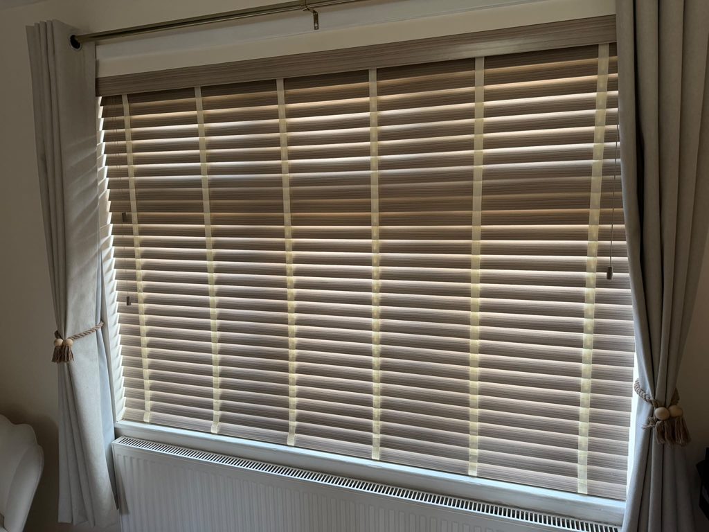 Large master bedroom window in Bilston with a 50mm faux wood venetian blind in Greige, cream ladder tapes and a valance across the top