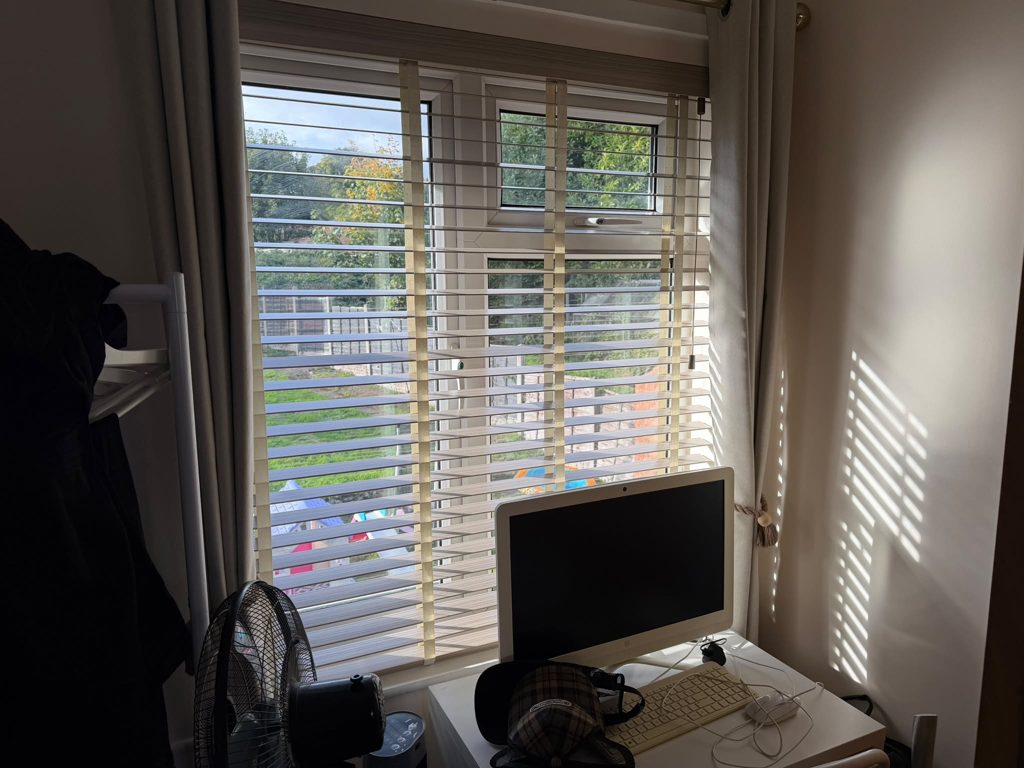 Master bedroom back window in Bilston with a 50mm Greige faux wood venetian blind, slats open and sunlight falling across the wall