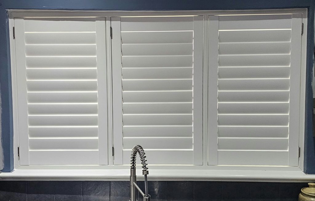 Three-panel Pure White ABS plastic shutters above a Bilston kitchen sink with the louvres closed