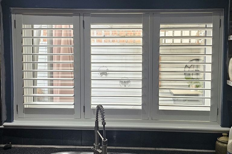 Three-panel Pure White ABS plastic shutters above a Bilston kitchen sink with the louvres open to the garden