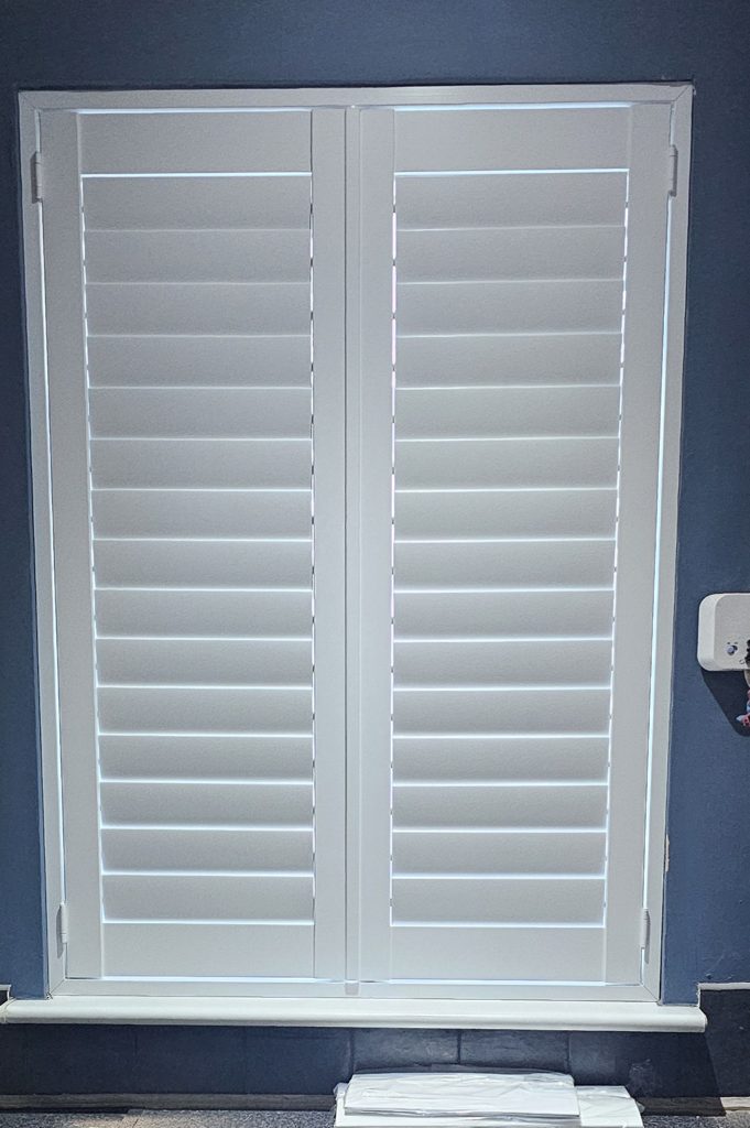 Two-panel Pure White ABS plastic shutter on the small Bilston kitchen window with the louvres closed