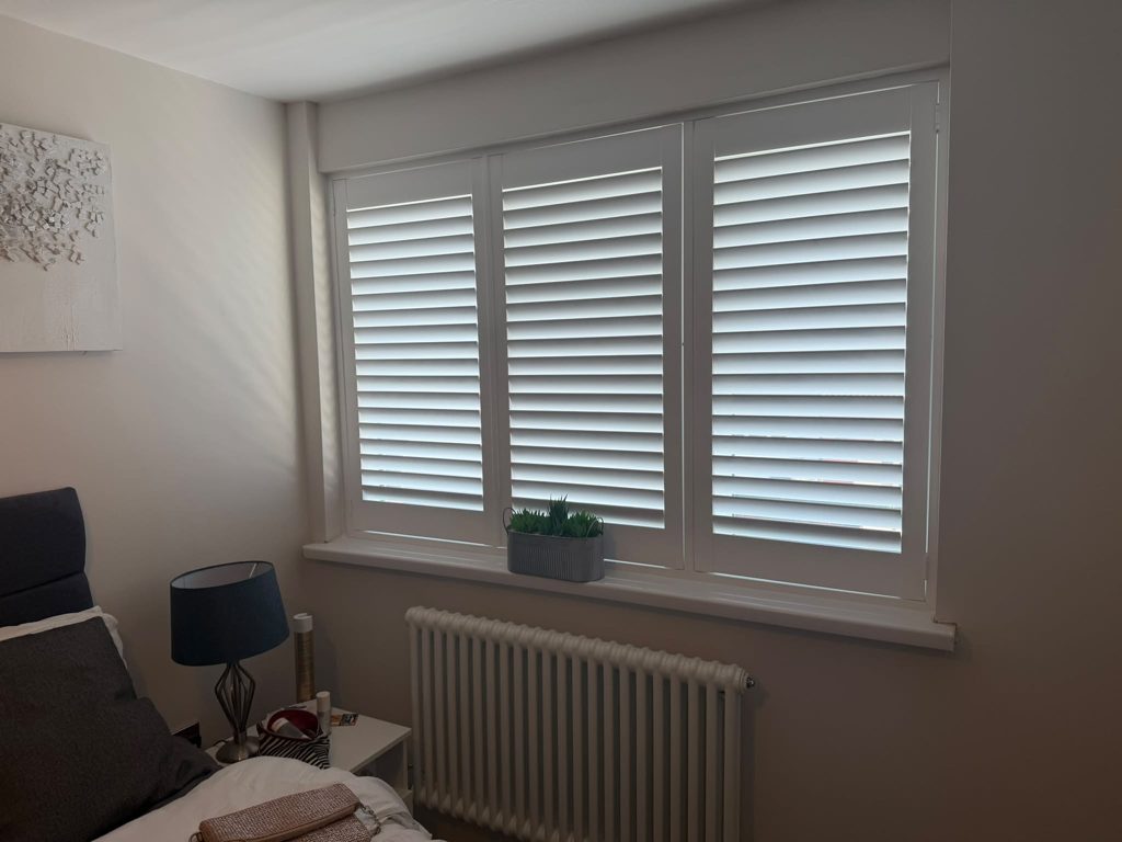 Three-panel full height Pure White shutters in a Halesowen bedroom with all louvres closed