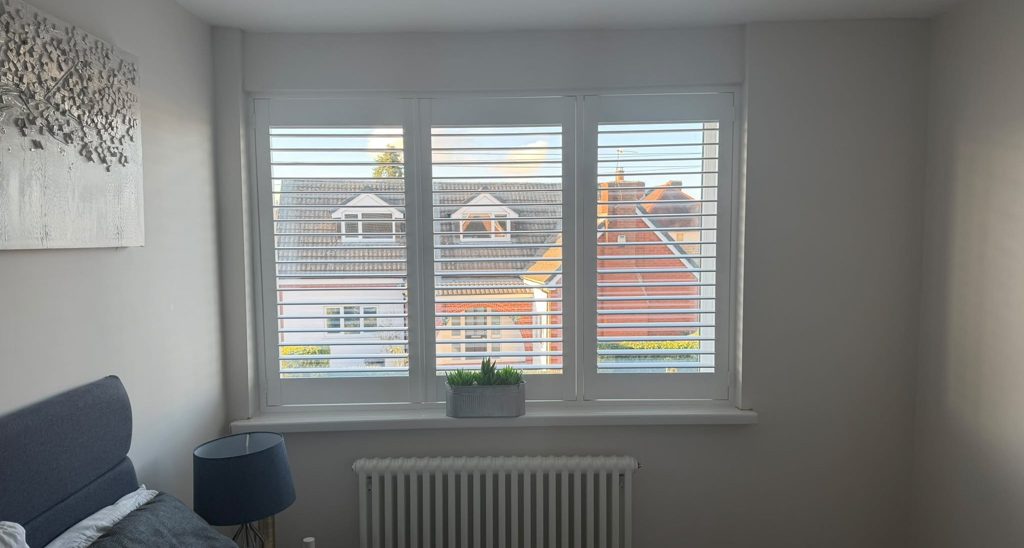 Wider view of the Halesowen bedroom with the three-panel shutters open above the radiator