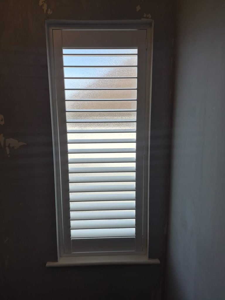 Single Pure White full height shutter with 76mm louvres and a 50% split tilt on a narrow landing window with privacy glass in Halesowen