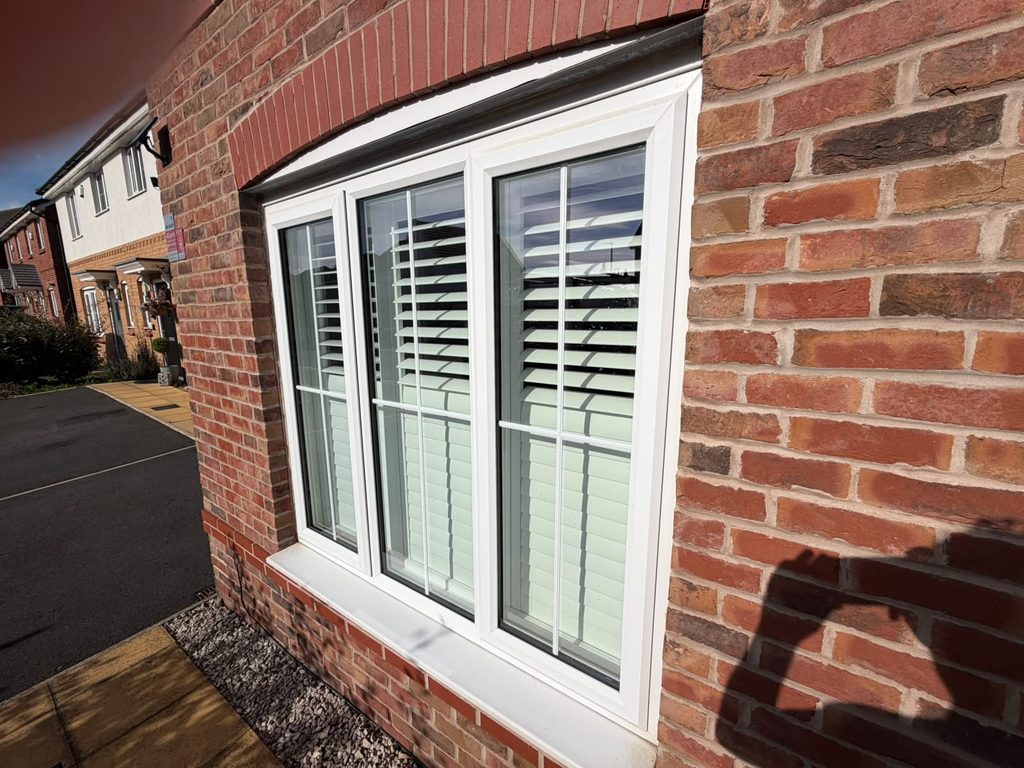 Outside view of the Smethwick living room window from the path, shutters set to split tilt with the top louvres open