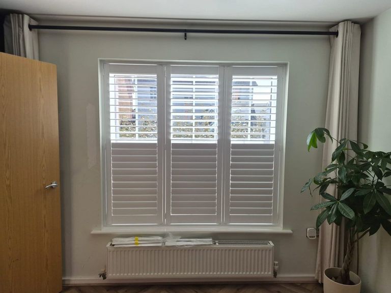 Three-panel full height Pure White Seattle shutters in a Smethwick living room, top louvres open and bottom louvres closed