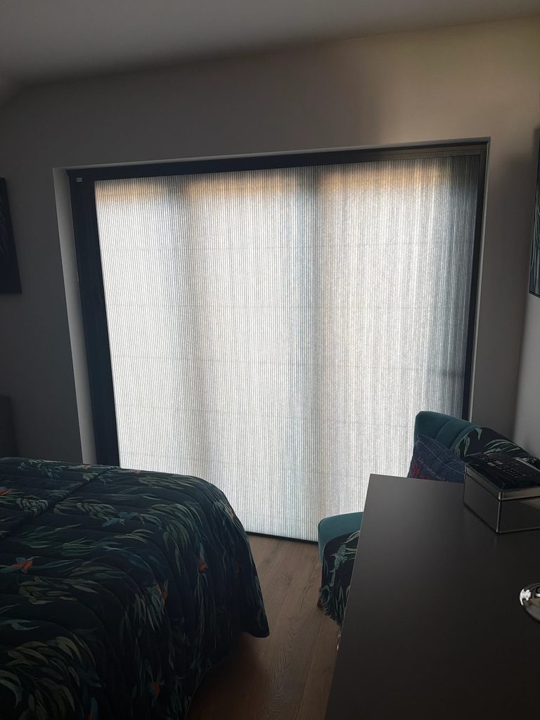 Dark grey Scene Set fabric drawn across bedroom bifold doors, letting soft daylight through